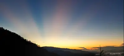a sunset over a mountain with the sun setting on the horizon at Infinite Stillness Farm in Buenos Aires