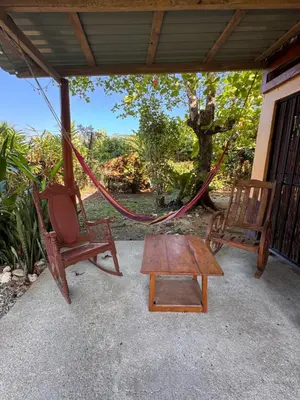 a porch with two chairs and a table and a swing at Casa Almendros in Cabuya