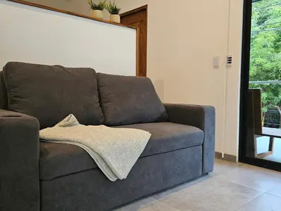 a couch in a living room with a blanket on it at Mystica in Playa Avellana