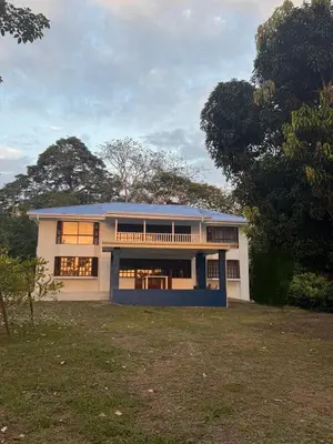 a large white house with a blue roof at Tivives Kikala Lodge 2 in Puntarenas