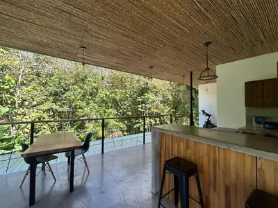 a kitchen with a table and a balcony with trees at Casa Joy - 3 Apartment Villa in the Hills of Santa Teresa in Santa Teresa Beach