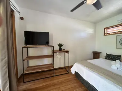 a bedroom with a bed and a flat screen tv at Casa Joy - 3 Apartment Villa in the Hills of Santa Teresa in Santa Teresa Beach