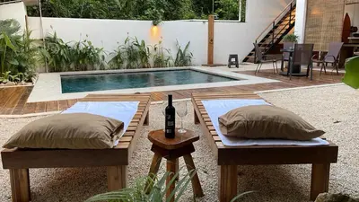 a pool with two pillows and a table with a bottle of wine at Casa Joy - 3 Apartment Villa in the Hills of Santa Teresa in Santa Teresa Beach