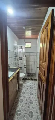 a bathroom with a toilet and a sink and a door at Abacaxi Hostel in Santa Teresa Beach