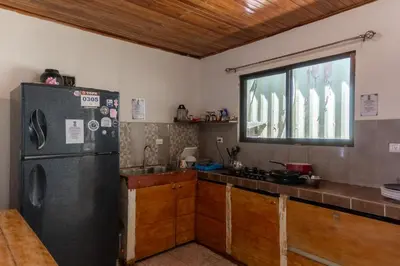 a kitchen with a refrigerator and a counter top at Abacaxi Hostel in Santa Teresa Beach
