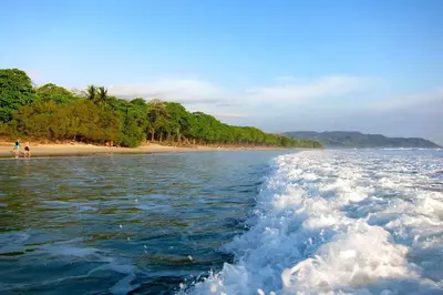 a boat in the water next to a beach at Abacaxi Hostel in Santa Teresa Beach