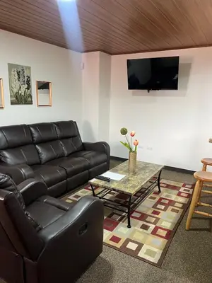 a living room with a leather couch and a table at Apartamento completo cerca del Aeropuerto y Parque Viva 5 personas in Guácima