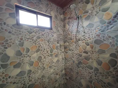a bathroom with a shower with a stone wall at Apartamento completo cerca del Aeropuerto y Parque Viva 5 personas in Guácima