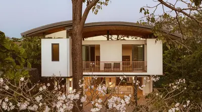 a house with a wrap around porch and a tree at Nimbu Vida in Tamarindo