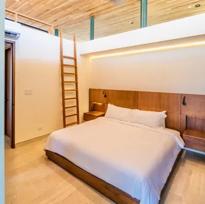 a bedroom with a bed with a ladder in it at Nimbu Vida in Tamarindo