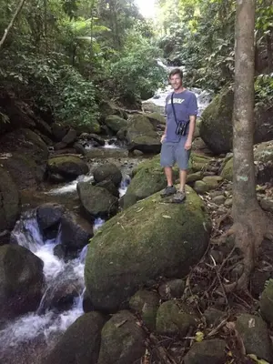 a man standing on a rock next to a stream at 2BR Toucans and Waterfalls- the garden cottage in Caña Blanca