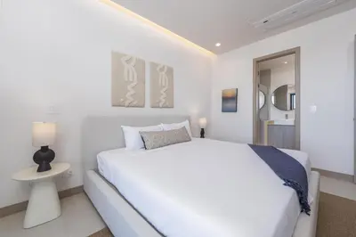 a white bedroom with a large white bed and a lamp at Brisa Mar, Ocean Views, Beach Club & Pools in Sardinal