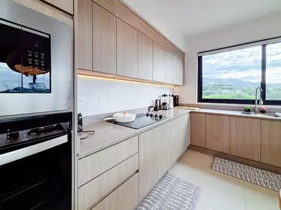 a kitchen with wooden cabinets and a large window at Sunset Terrace at Naumi, Ocean Views & Beach Club in Sardinal