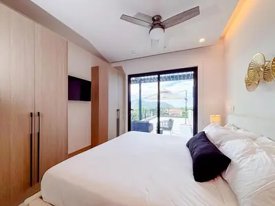 a bedroom with a large white bed and a window at Sunset Terrace at Naumi, Ocean Views & Beach Club in Sardinal