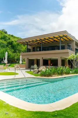 a resort with a swimming pool in front of a building at Vista Paz Condo, Ocean Views & Beach Club in Sardinal