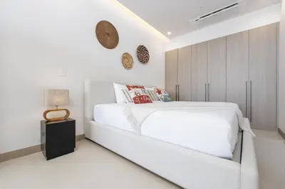 a white bedroom with a white bed and a clock on the wall at Casa Mint, Ocean Views, Pools, Gym & Beach Club in Sardinal