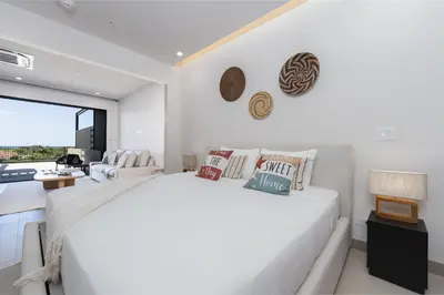a white bedroom with a large bed and a living room at Casa Mint, Ocean Views, Pools, Gym & Beach Club in Sardinal