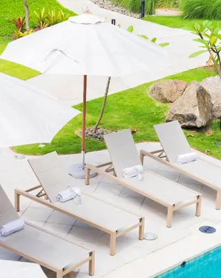 a group of lounge chairs and an umbrella next to a pool at Casa Mint, Ocean Views, Pools, Gym & Beach Club in Sardinal