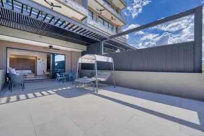 a patio with a swing on the side of a building at Casa Mint, Ocean Views, Pools, Gym & Beach Club in Sardinal