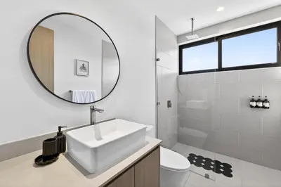 a white bathroom with a sink and a mirror at Tropics at Naumi, Ocean Views, Gym & Pools in Sardinal