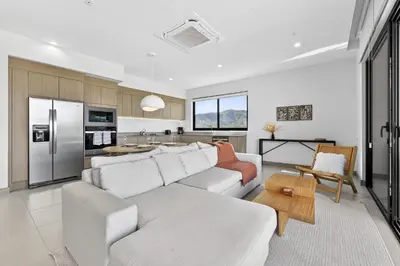 a living room with a white couch and a kitchen at Tropics at Naumi, Ocean Views, Gym & Pools in Sardinal