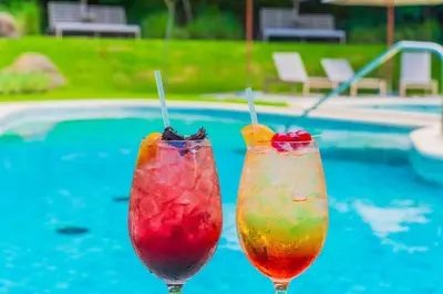 two colorful cocktails sitting next to a swimming pool at Costa Azul Condo, Ocean View & Beach Club in Sardinal