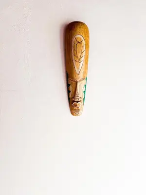 a wooden mask hanging on a white wall at Selva Partners La Fortuna in Guaria