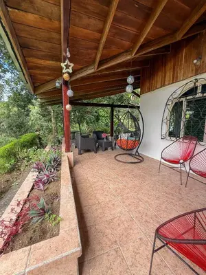 a patio with red chairs and a wooden ceiling at Selva Partners La Fortuna in Guaria