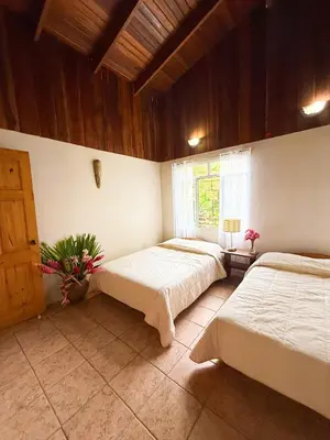 a bedroom with two beds and a window at Selva Partners La Fortuna in Guaria