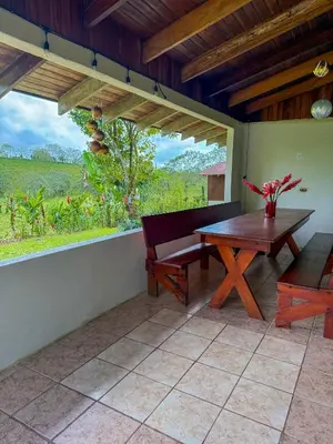 a patio with a wooden table and a bench at Selva Partners La Fortuna in Guaria