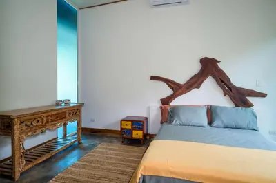 a bedroom with a bed with a wooden headboard and a table at Casa Bromelia in Portalón