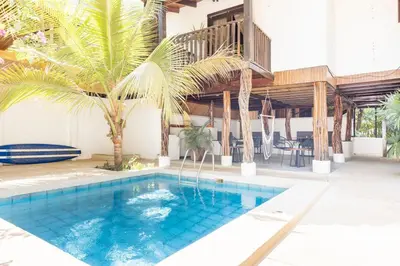 a swimming pool with palm trees and a house at La Buena vida Cabina 1 in Playa Grande