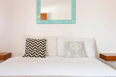 a white bed with two pillows and a mirror at La Buena vida Cabina 1 in Playa Grande
