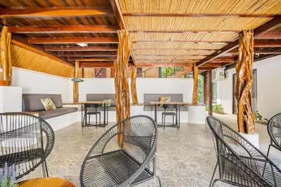 a patio with chairs and tables and a wooden ceiling at La Buena vida Cabina 3 in Playa Grande