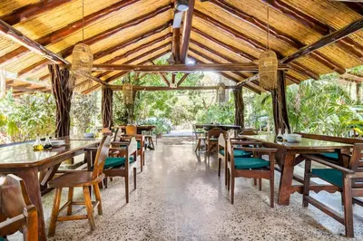 a dining room with wooden tables and chairs at La Buena vida Cabina 3 in Playa Grande