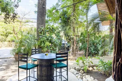 a table and chairs in a garden with trees at La Buena vida Cabina 3 in Playa Grande