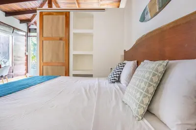 a bedroom with a white bed with a wooden headboard at La Buena vida Cabina 4 in Playa Grande