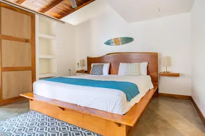 a bedroom with a large bed with a wooden headboard at La Buena vida Cabina 4 in Playa Grande