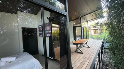 a glass house with a wooden table on a deck at Bamboo grove villa in San Isidro