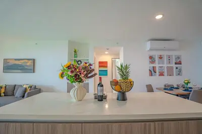 a kitchen with a counter with flowers and a bottle of wine at Panoramic ocean view condo-pools-gym-fast internet in Jacó