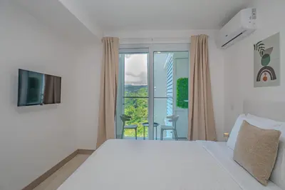 a white bedroom with a bed and a balcony at Panoramic ocean view condo-pools-gym-fast internet in Jacó