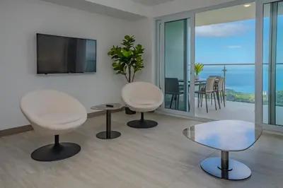 a living room with two chairs and a table at Panoramic ocean view condo-pools-gym-fast internet in Jacó