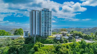 a tall building in the middle of a city at Panoramic ocean view condo-pools-gym-fast internet in Jacó