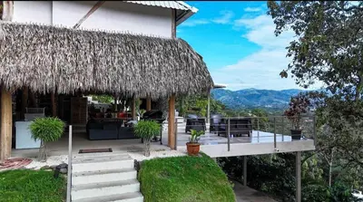 a house with a thatched roof and a patio at Silencio Verde in Atenas