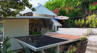 a picnic table in front of a house with an umbrella at Silencio Verde in Atenas