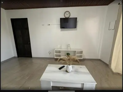 a living room with a table and a tv on a wall at PURA VIDA AIRPORT STAY FREE SHUTTLe in Alajuela City