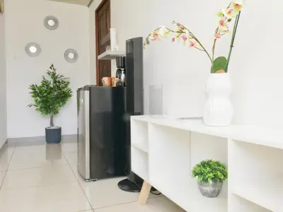 a living room with a refrigerator and flowers in a vase at PURA VIDA AIRPORT STAY FREE SHUTTLe in Alajuela City