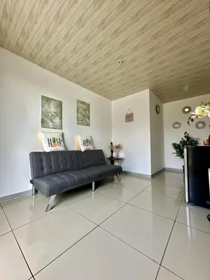 a black couch in a living room with a wooden ceiling at PURA VIDA AIRPORT STAY FREE SHUTTLe in Alajuela City