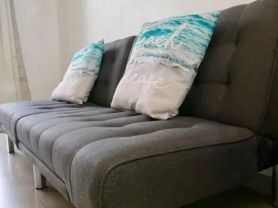 a brown couch with two pillows on top of it at PURA VIDA AIRPORT STAY FREE SHUTTLe in Alajuela City