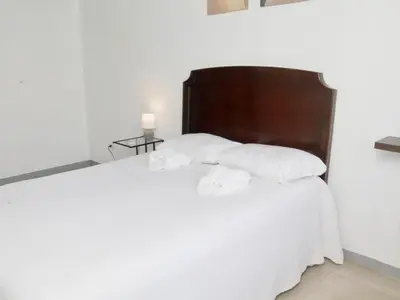 a bed with white sheets and pillows at PURA VIDA AIRPORT STAY FREE SHUTTLe in Alajuela City